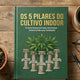 Livro “Os 5 Pilares do Cultivo Indoor” sobre mesa de madeira com muda em vaso, café, óculos e caneta, representando guia essencial para iniciantes no cultivo indoor.